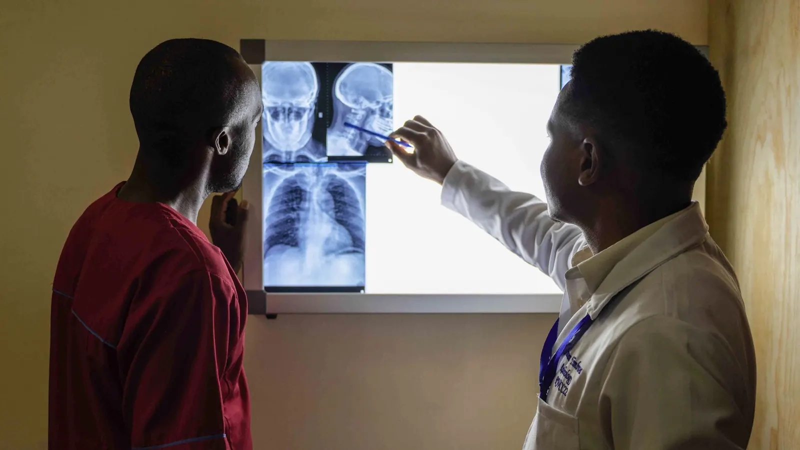Clinician pointing out details on chest and skull X-rays on a light box